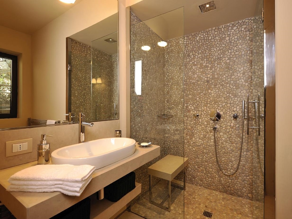 A tiled bathroom with walk-in shower and large basin