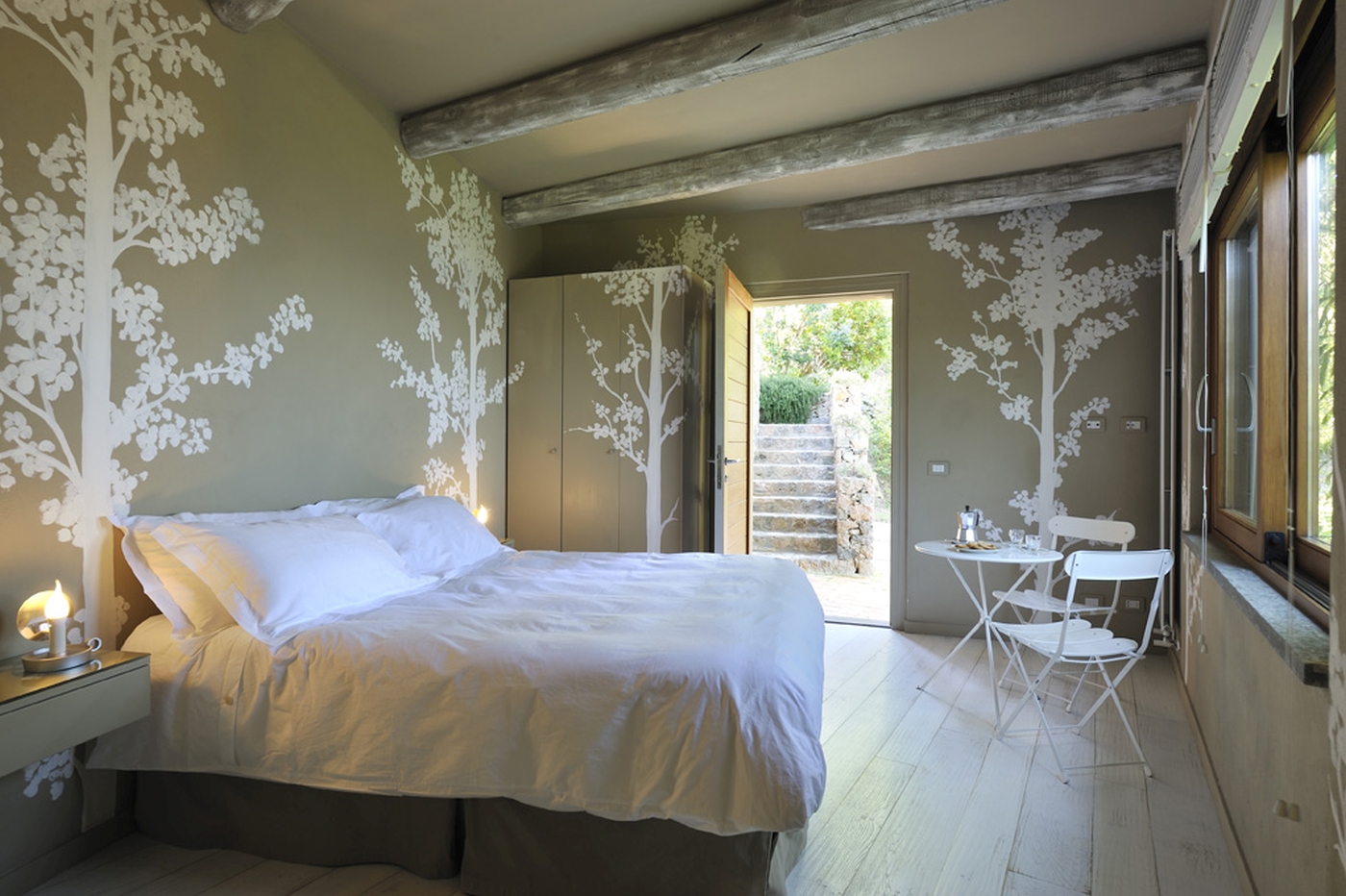 A double bedroom with tree wallpaper and seating area