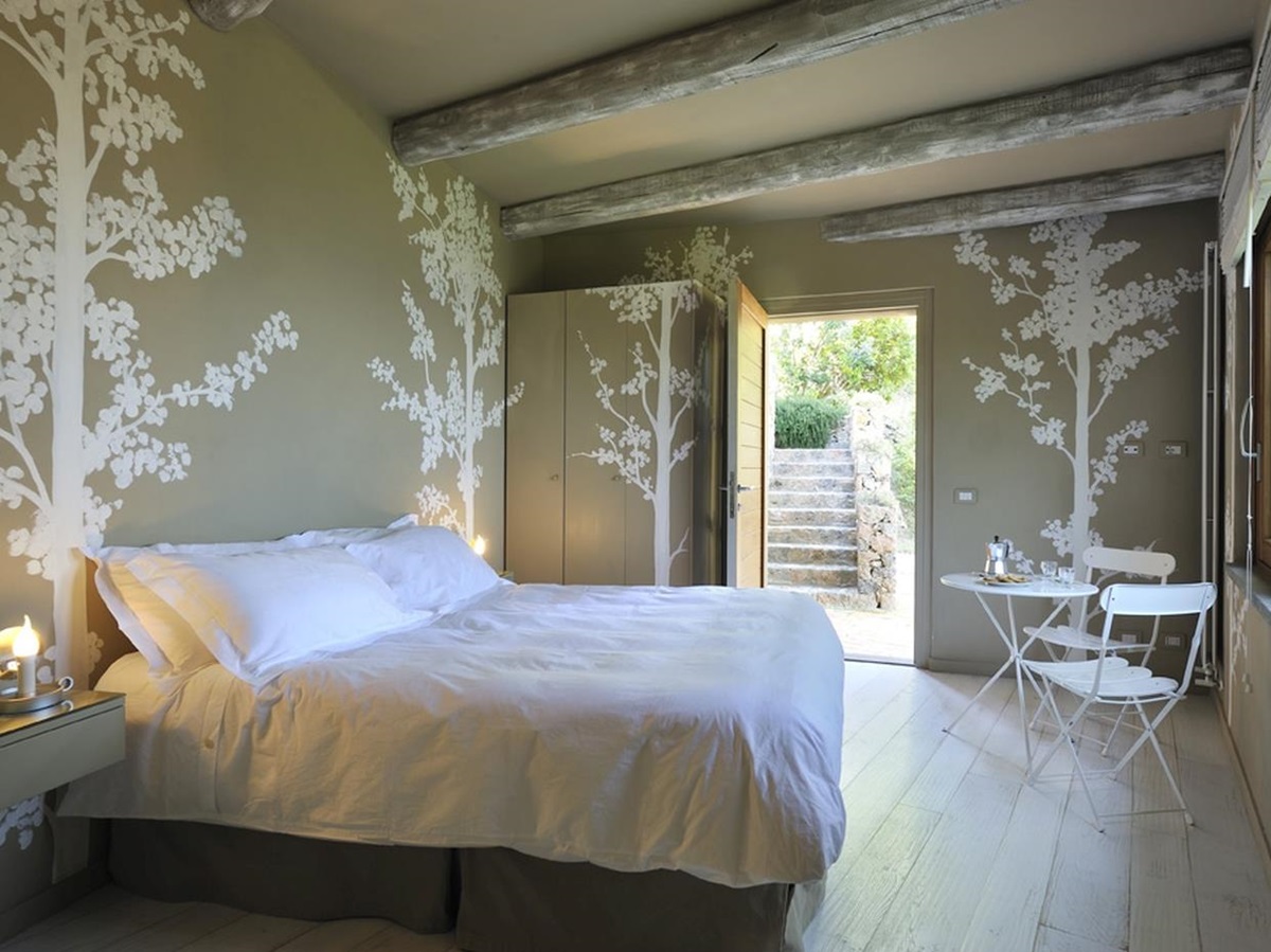 A double bedroom with tree wallpaper and seating area