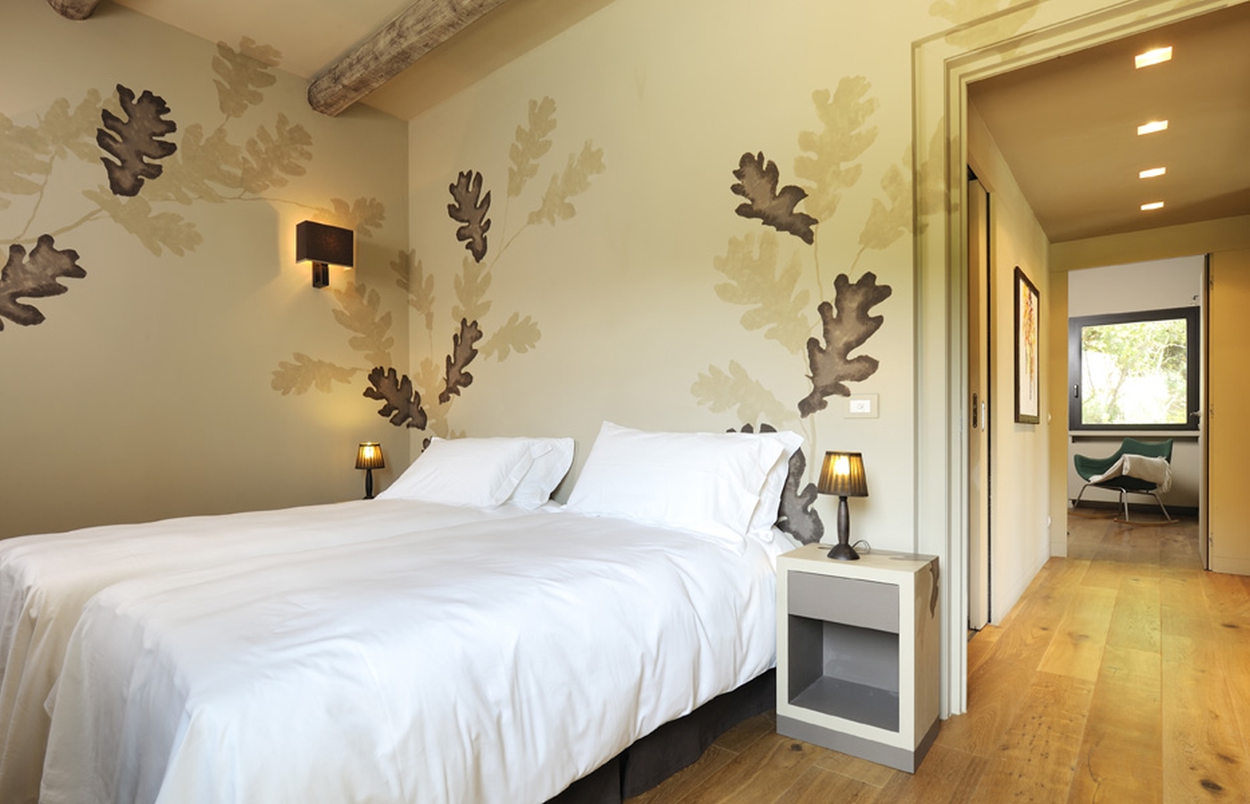 Twin bedroom with leaf decorations and view down wooden floored corridor