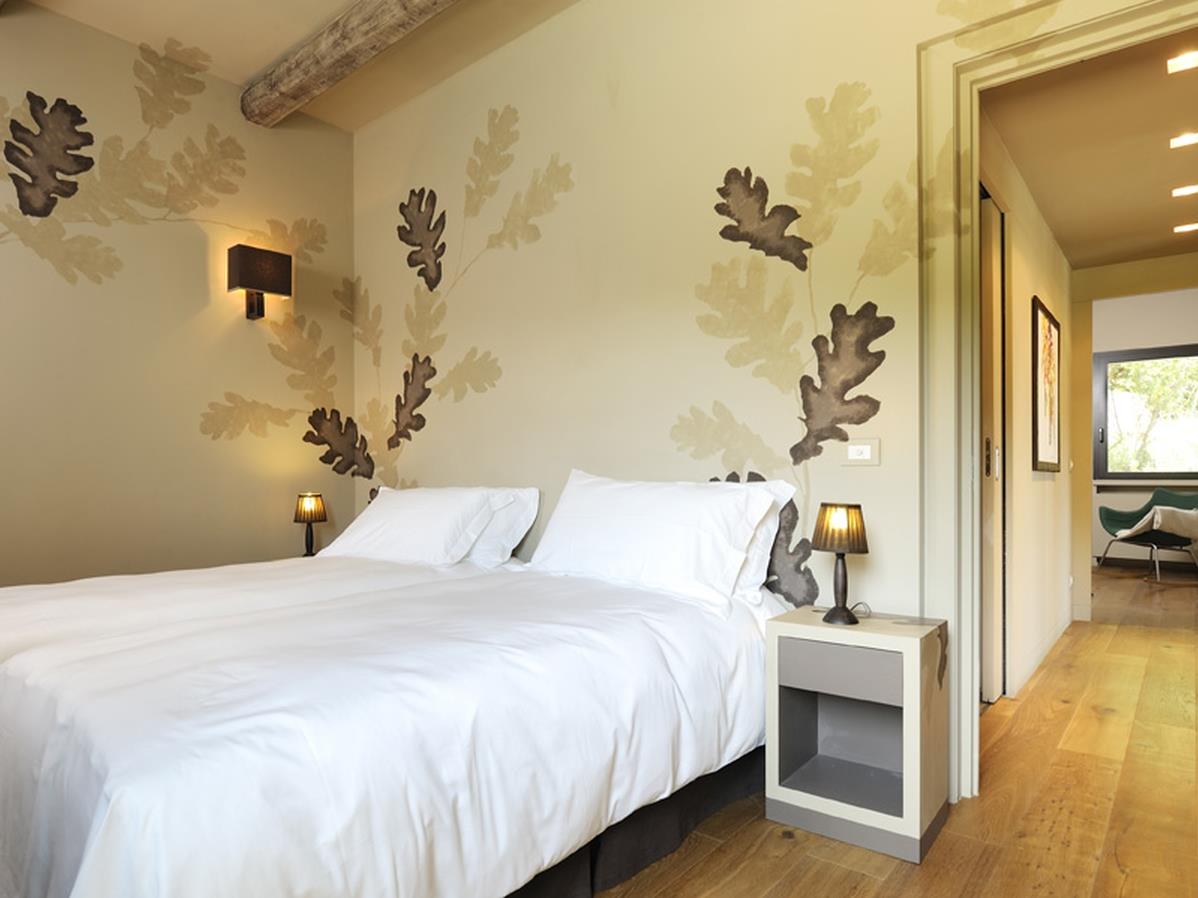 Twin bedroom with leaf decorations and view down wooden floored corridor