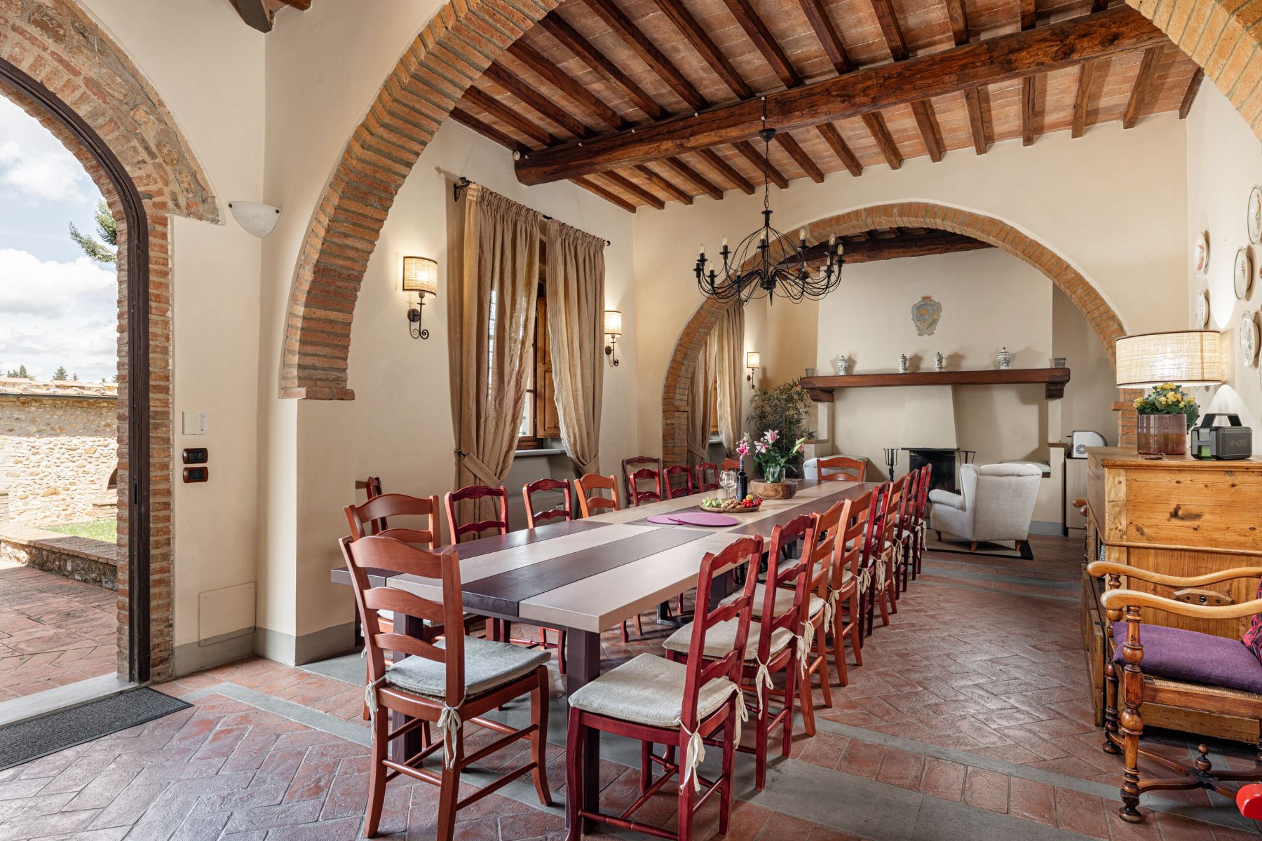 Indoor dining room with long table and red chairs at Villa Il Sole in Tuscany