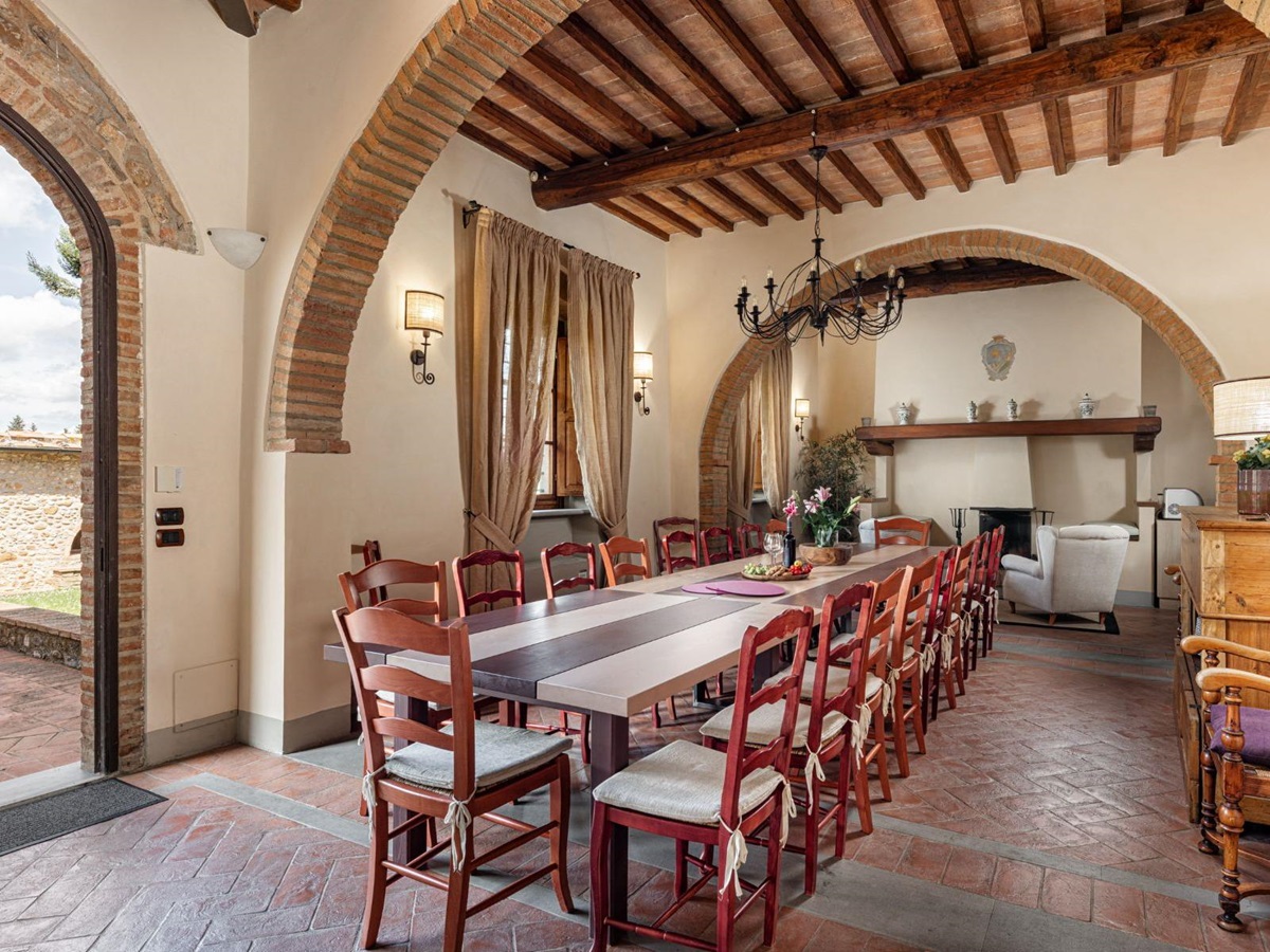 Indoor dining room with long table and red chairs at Villa Il Sole in Tuscany