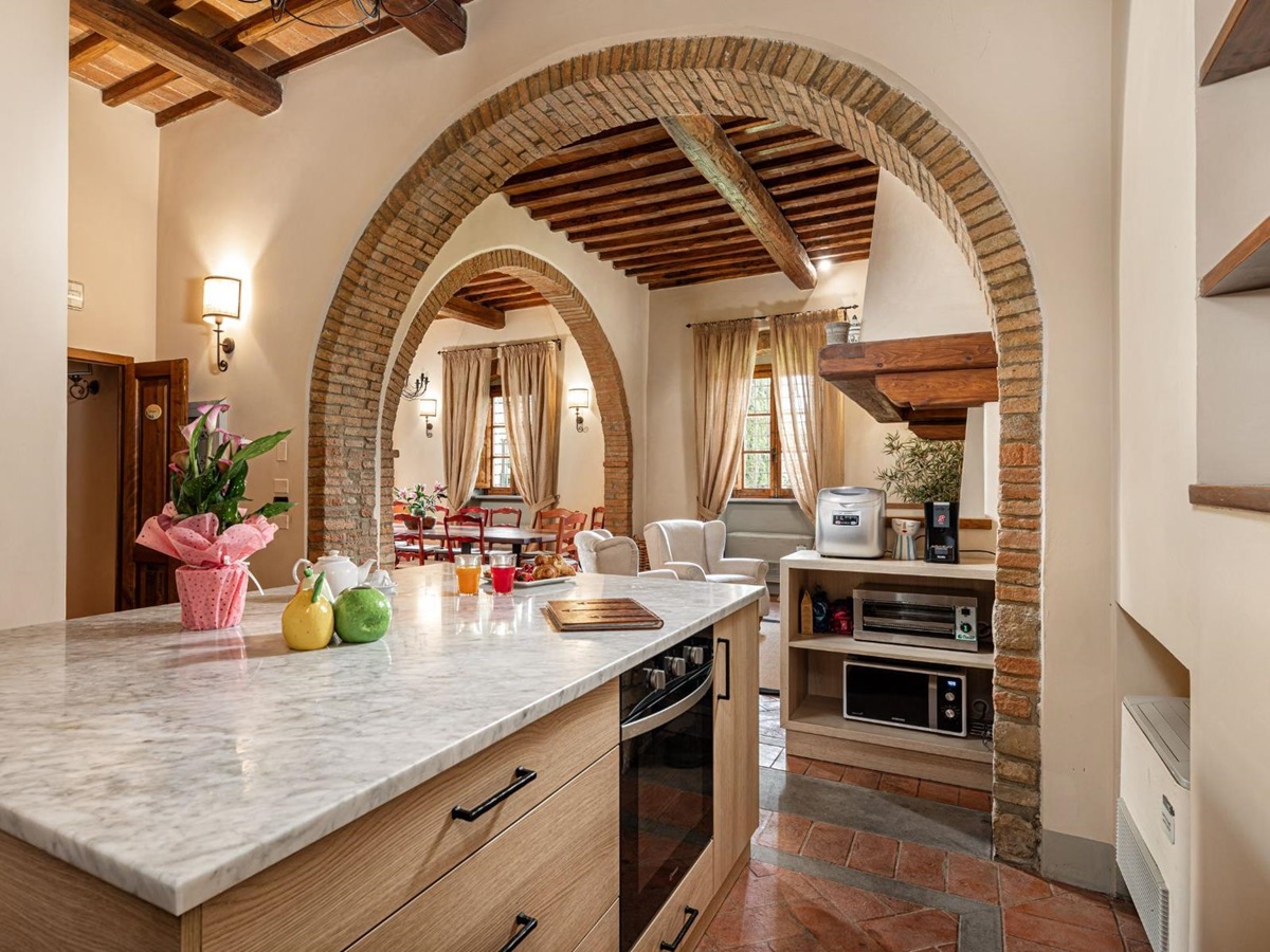 Kitchen area with a marble island and view of the indoor lounge area at Villa Il Sole in Tuscany