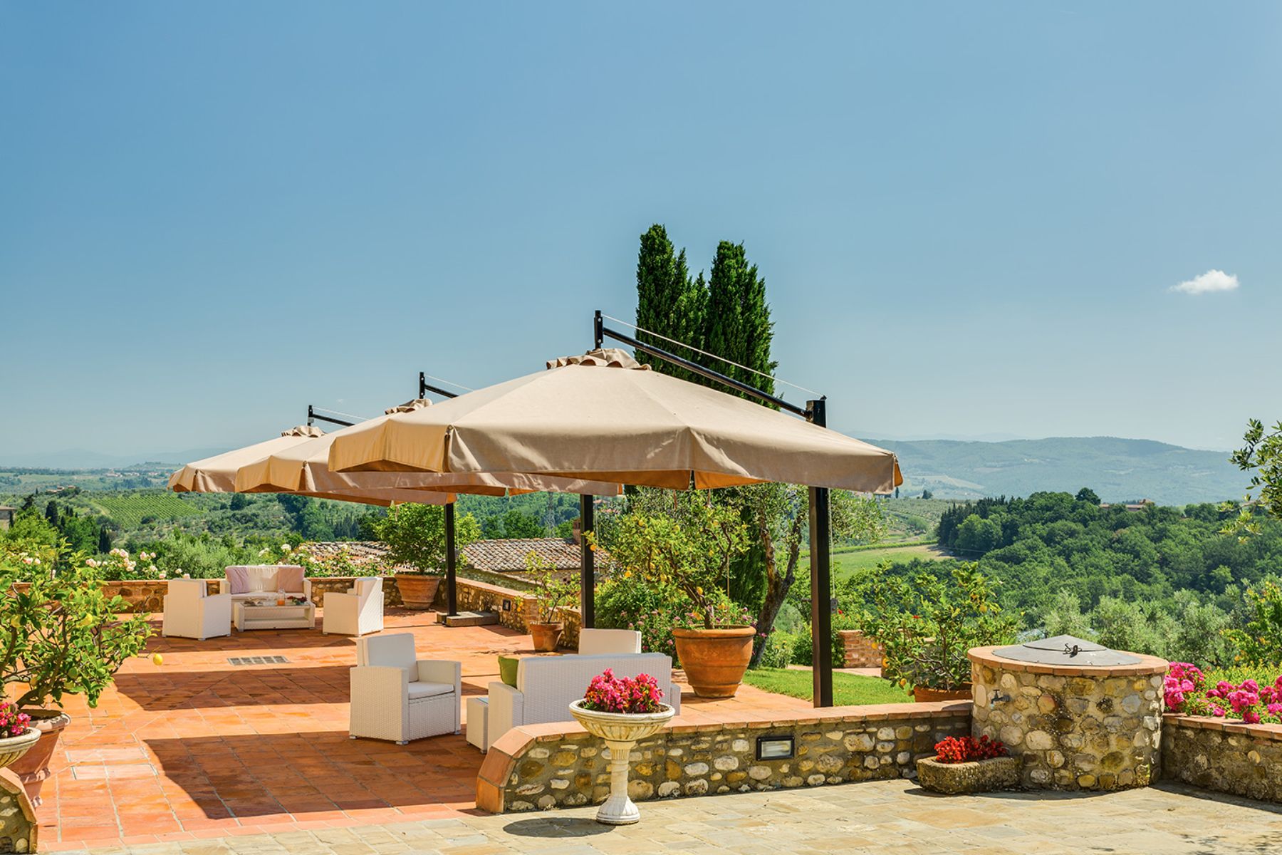 Outdoor lounge area under large umbrellas on the patio at Villa Il Sole in Tuscany