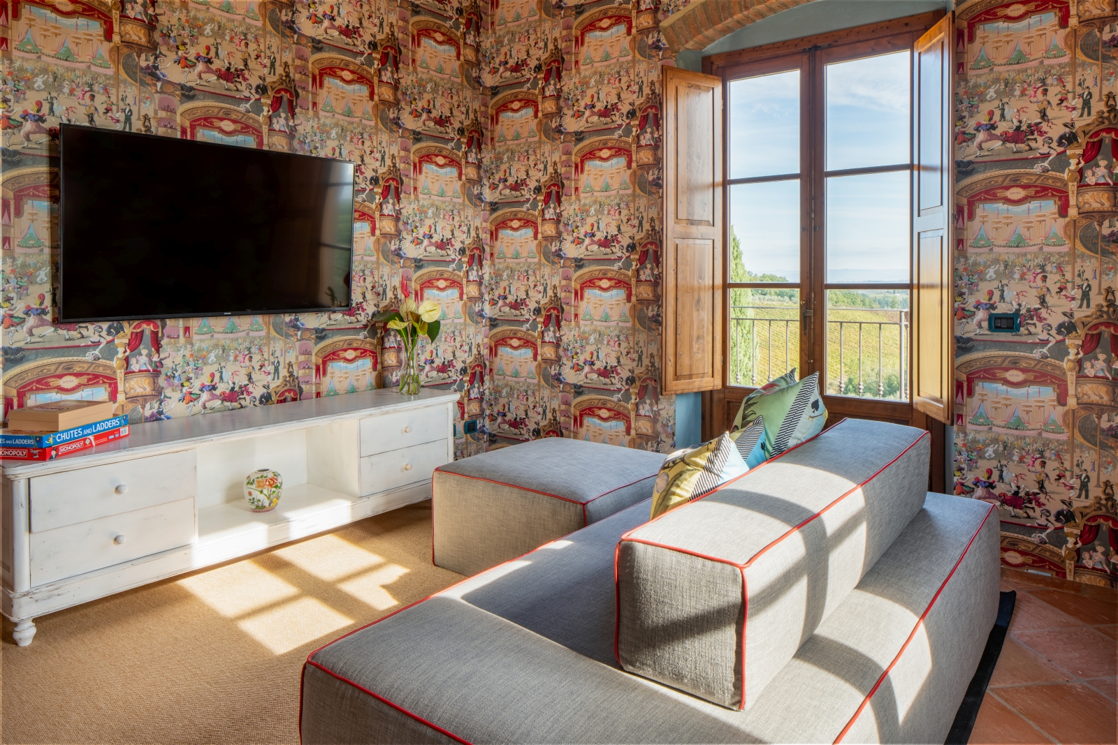Sofas with colourful wallpaper and large TV at Villa Il Sole in Tuscany