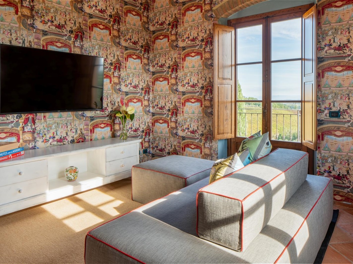 Sofas with colourful wallpaper and large TV at Villa Il Sole in Tuscany