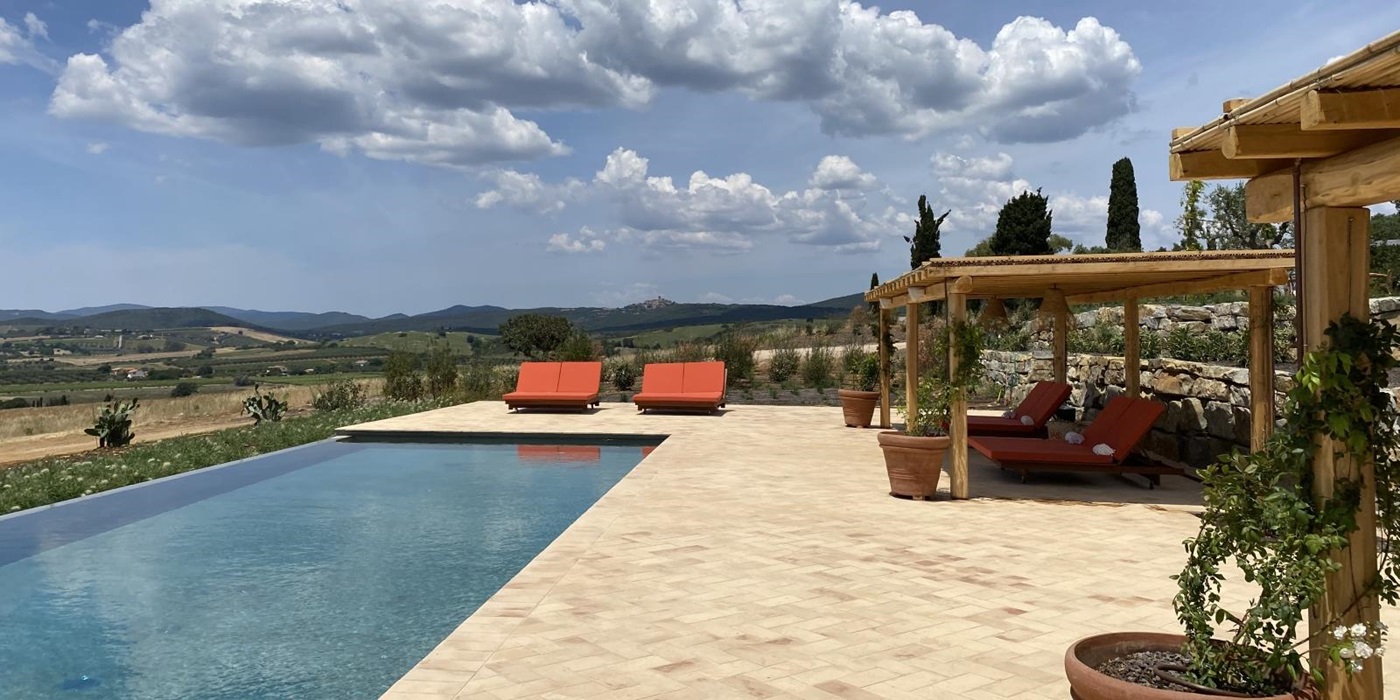 Pool and pool area with sun loungers, plants and countryside view at Villa Jacaranda in Tuscany, Italy