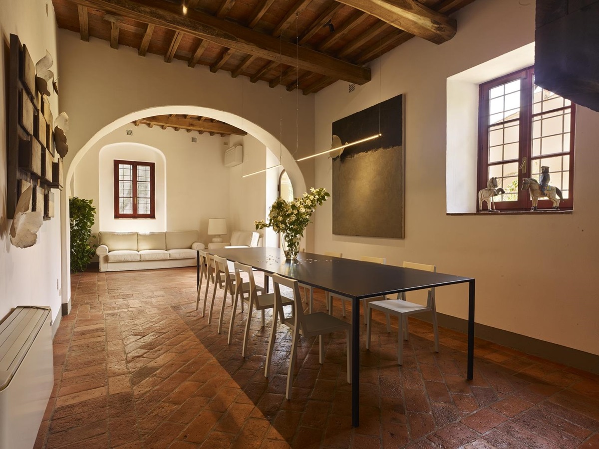 Dining room with long dining table, artwork, horse statues and sofas at Villa La Castellana in Tuscany, Italy