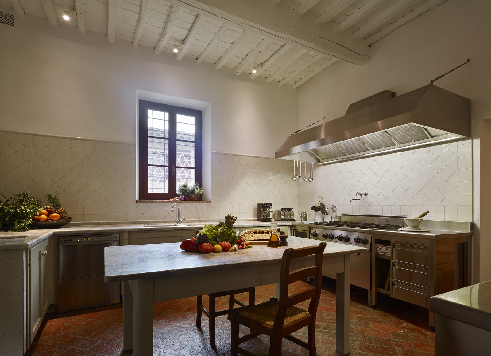 Kitchen with island, chairs, fresh food, appliances and window at Villa La Castellana in Tuscany, Italy