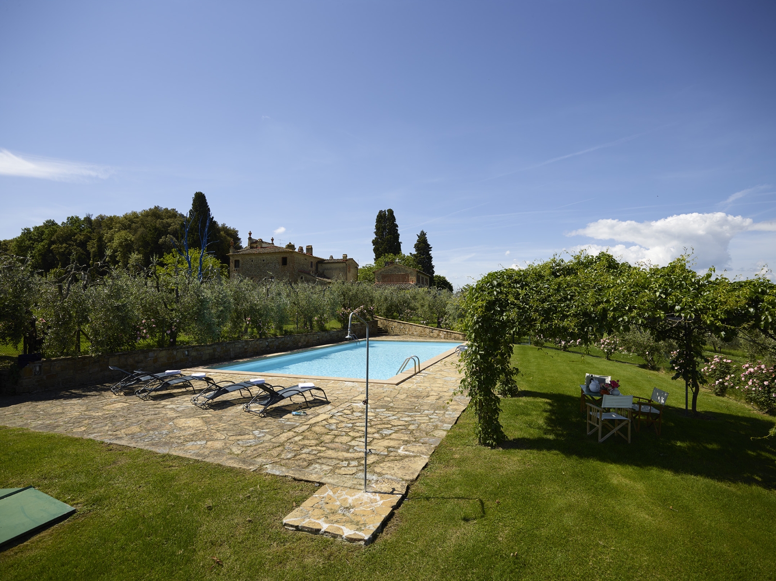 Pool, pool area and garden with sun loungers, shower, chairs and arbour at Villa La Castellana in Tuscany, Italy