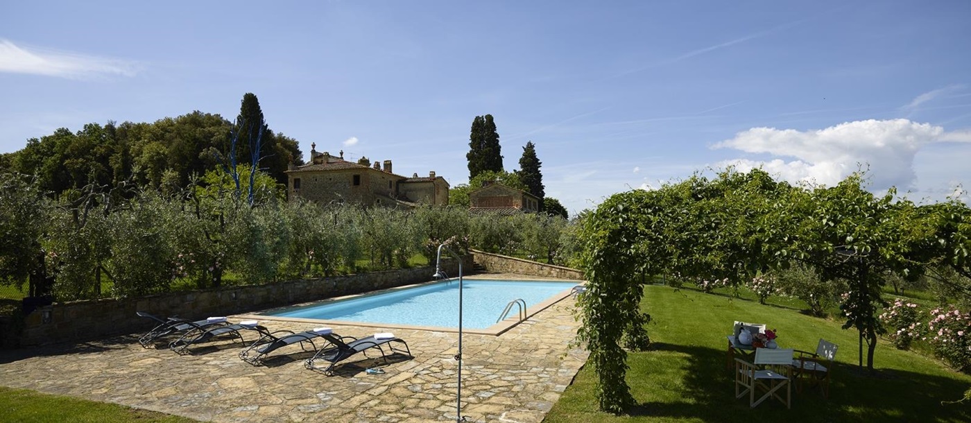 Pool, pool area and garden with sun loungers, shower, chairs and arbour at Villa La Castellana in Tuscany, Italy