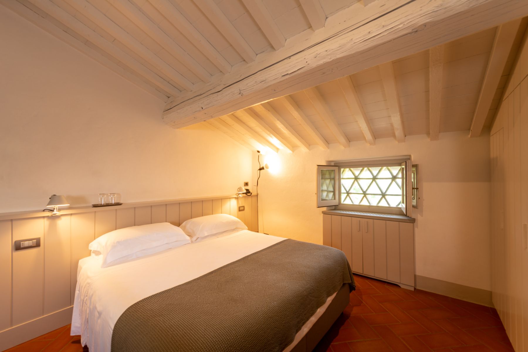 Bedroom in the attic with large double bed and tiled flooring at Villa Luce in Tuscany