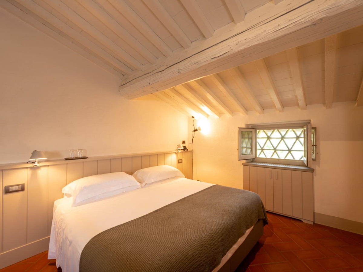 Bedroom in the attic with large double bed and tiled flooring at Villa Luce in Tuscany