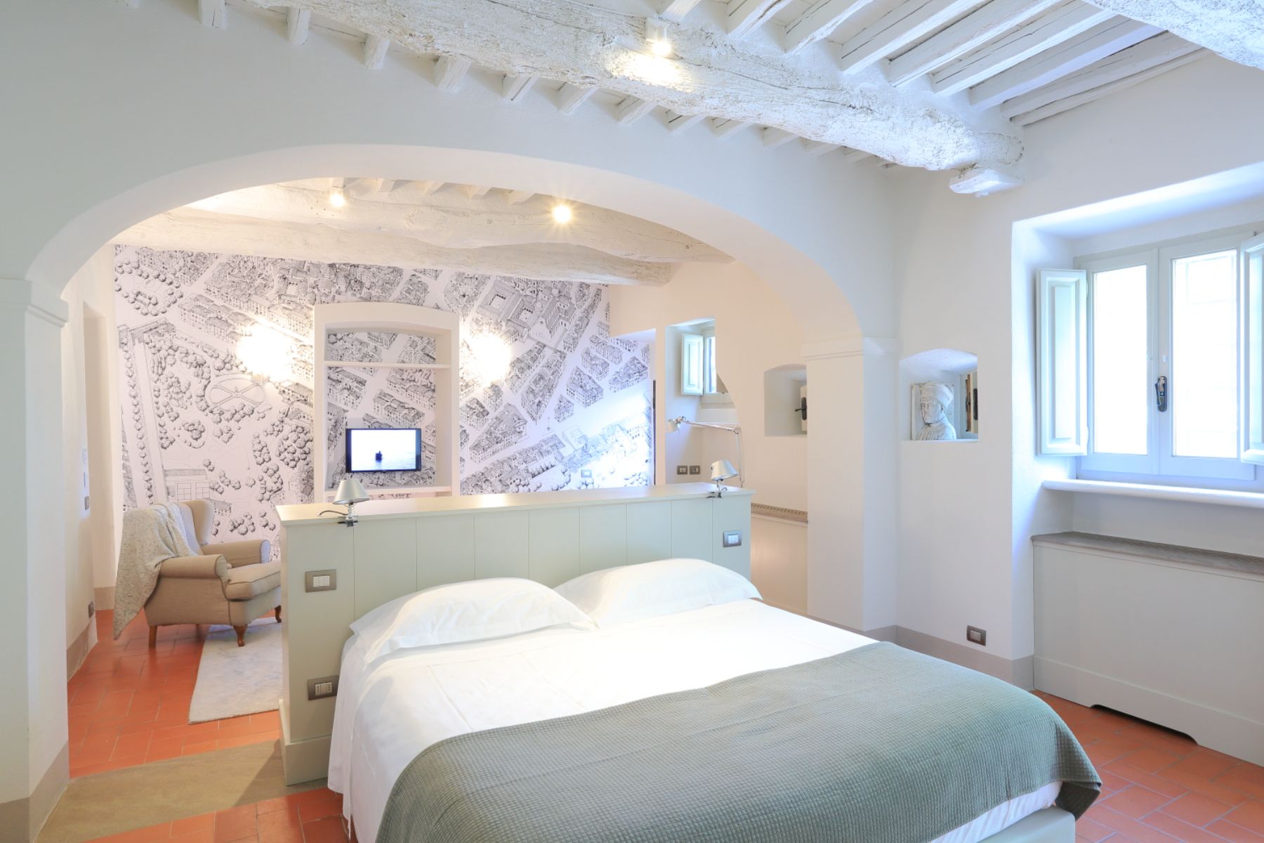 Large modern bedroom with double bed and an armchair at Villa Luce in Tuscany