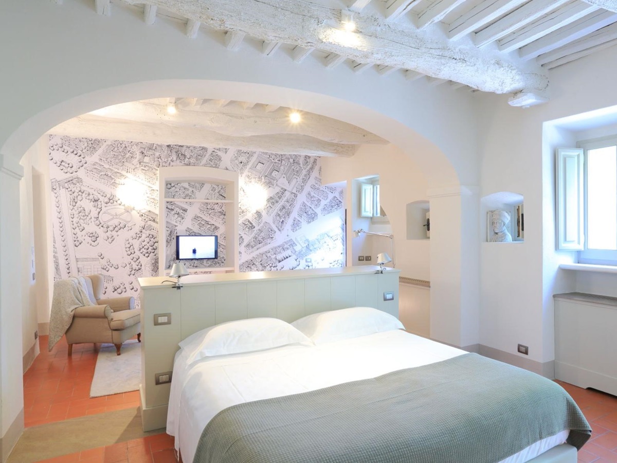 Large modern bedroom with double bed and an armchair at Villa Luce in Tuscany