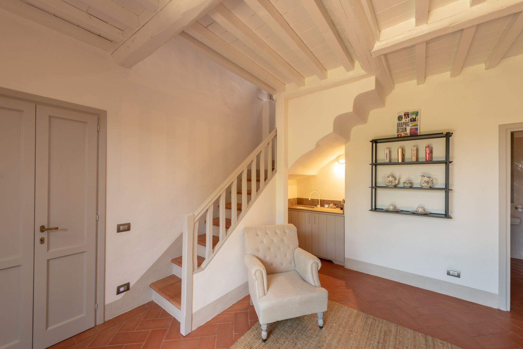 Small lounge area with a kitchen area and stairs leading to bedroom upstairs at Villa Luce in Tuscany