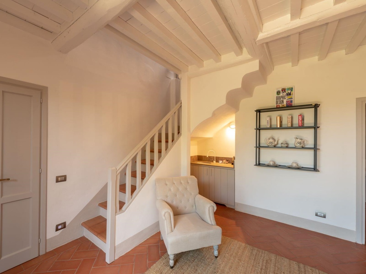 Small lounge area with a kitchen area and stairs leading to bedroom upstairs at Villa Luce in Tuscany