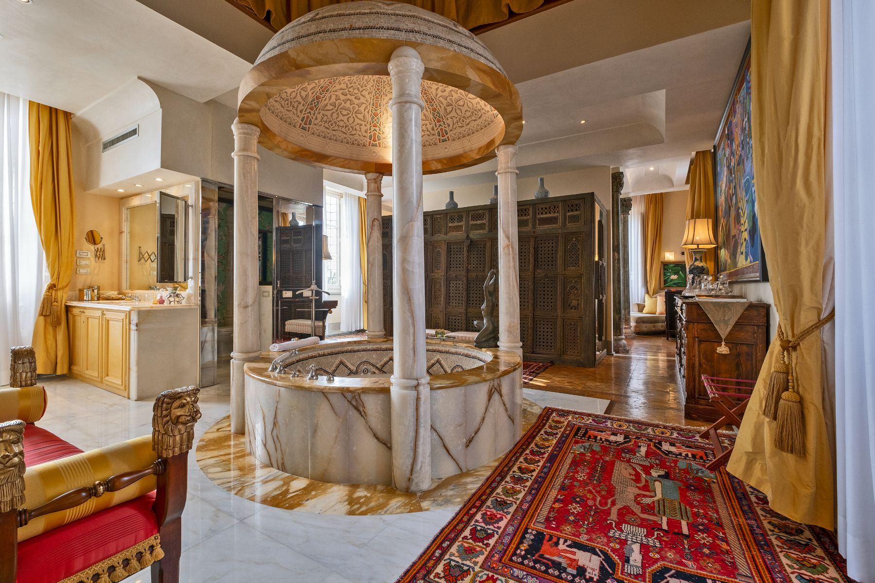 Bathroom with large tiled bath in the middle of the room surrounded by antique furniture at Villa Machiavelli in Tuscany