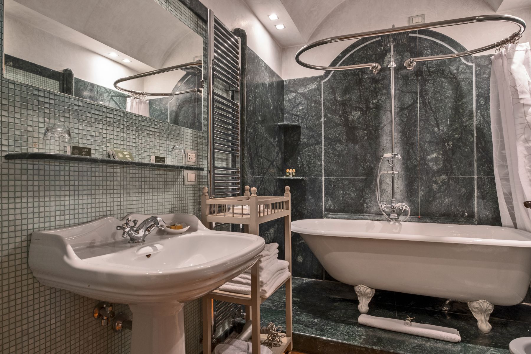 Bathroom with grey tiled interiors featuring a bath tub and basin at Villa Machiavelli in Tuscany