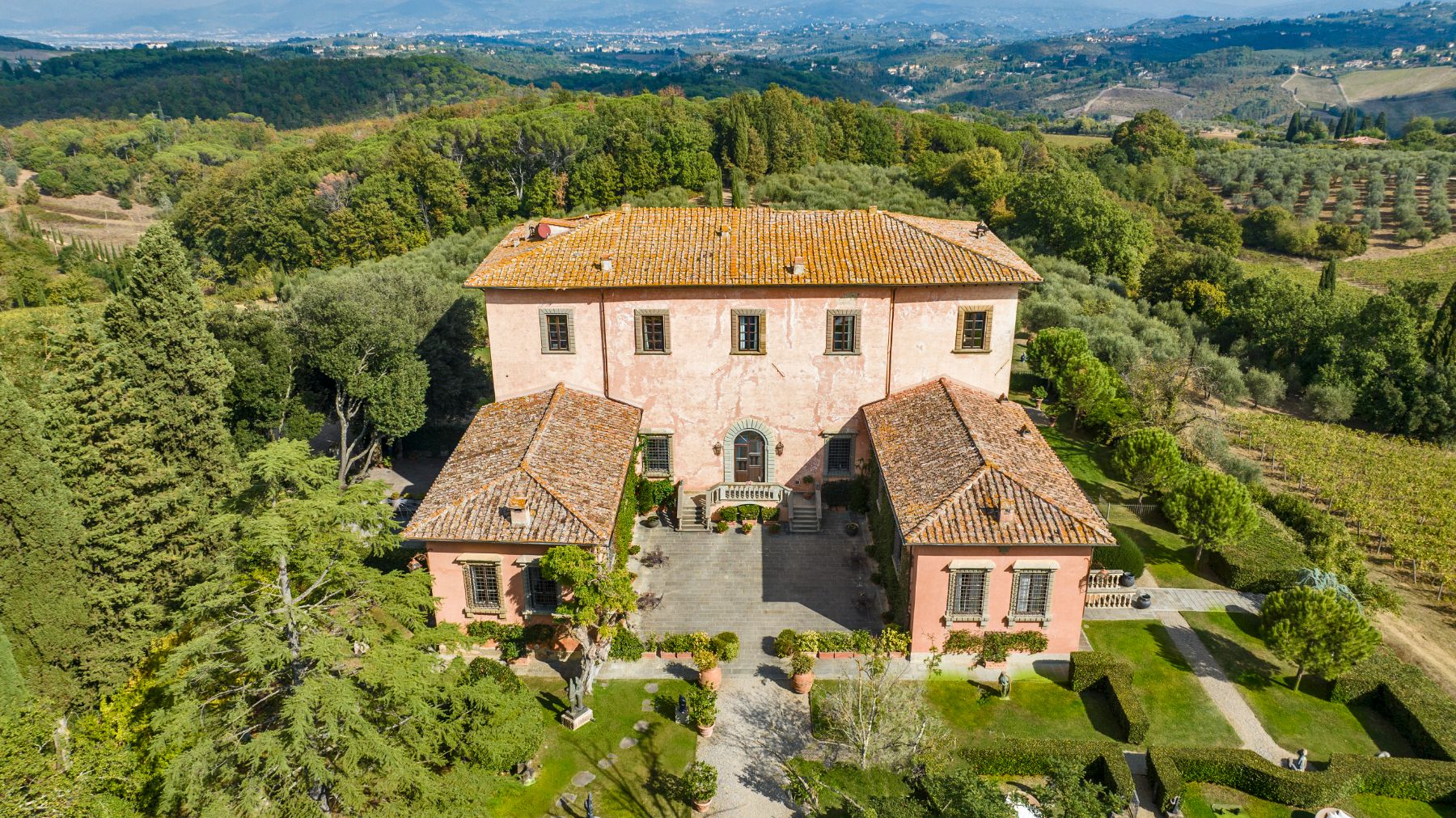 View of the front of the villa and the gardens surrounded by trees at Villa Machiavelli in Tuscany