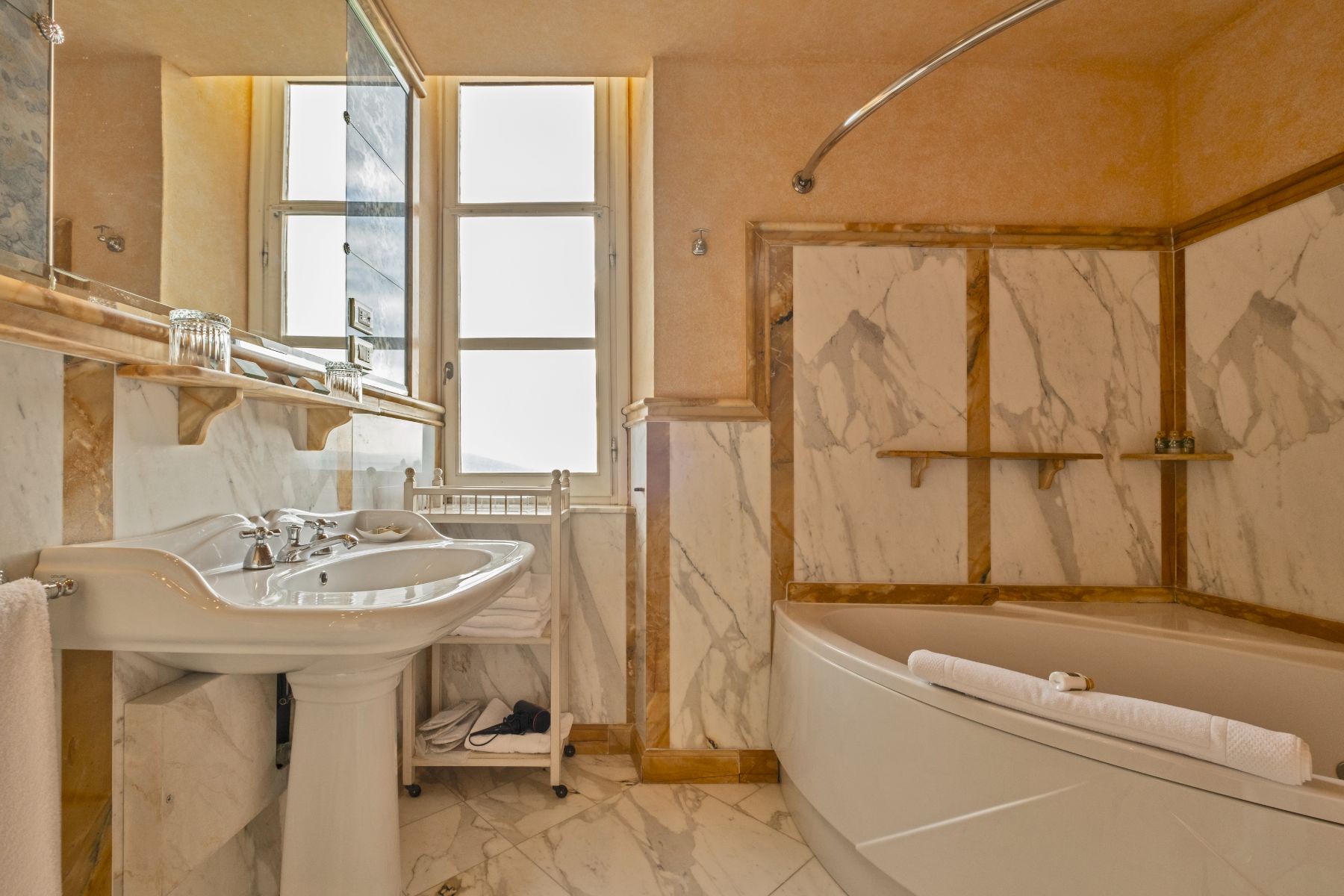 Bathroom with marble interiors in white and gold featuring a bath tub and a basin in Villa Machiavelli in Tuscany