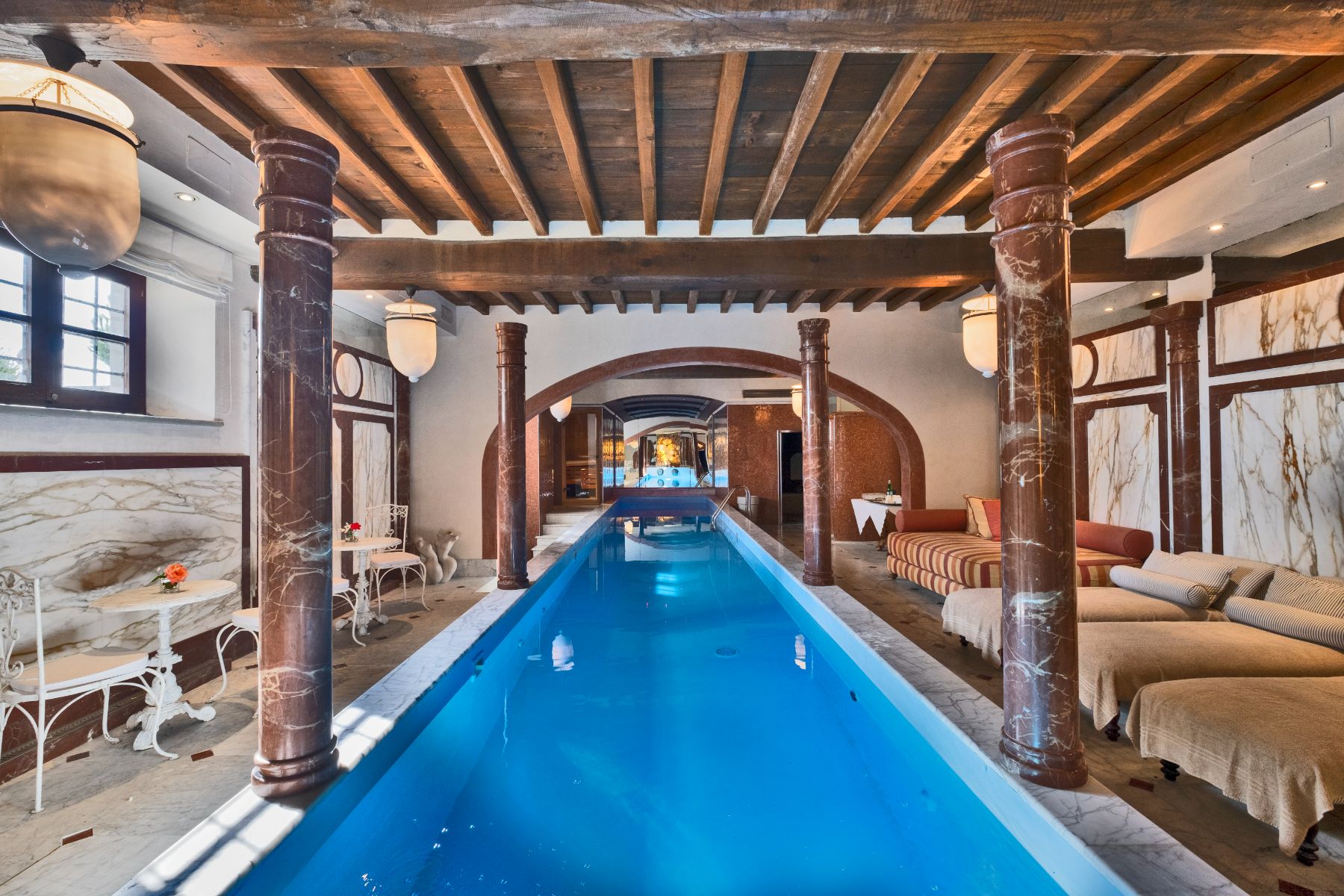 Indoor swimming  pool featuring poolside beds and tables