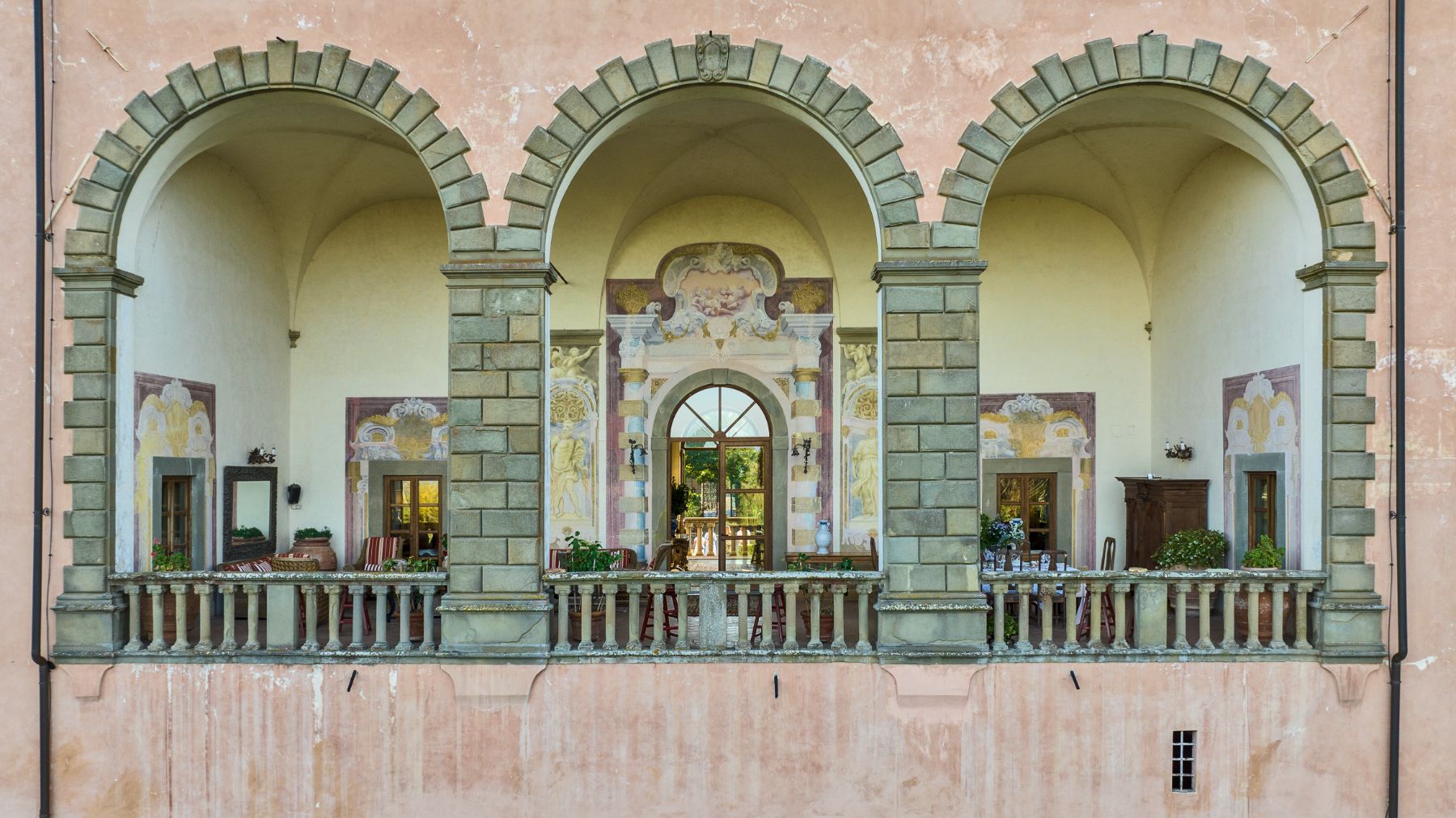 External terrace view with three large arches and artwork at Villa Machiavelli in Tuscany
