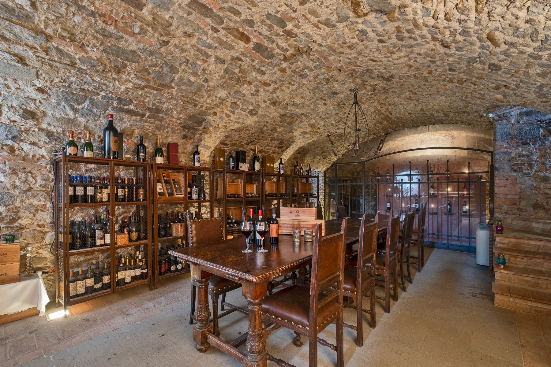Underground wine cellar featuring a large wine cabinet and a long wooden table at Villa Machiavelli in Tuscany