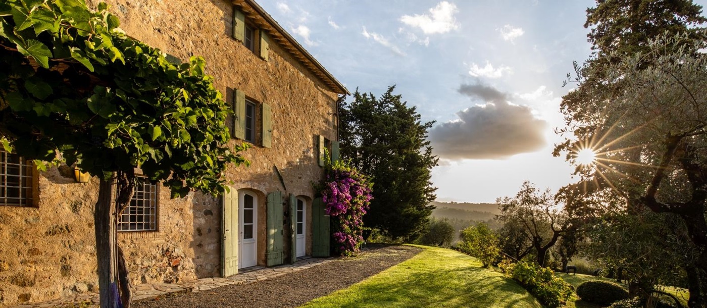 Exterior of villa with vines, flowers and grass at Villa Ortensia in Tuscany, Italy
