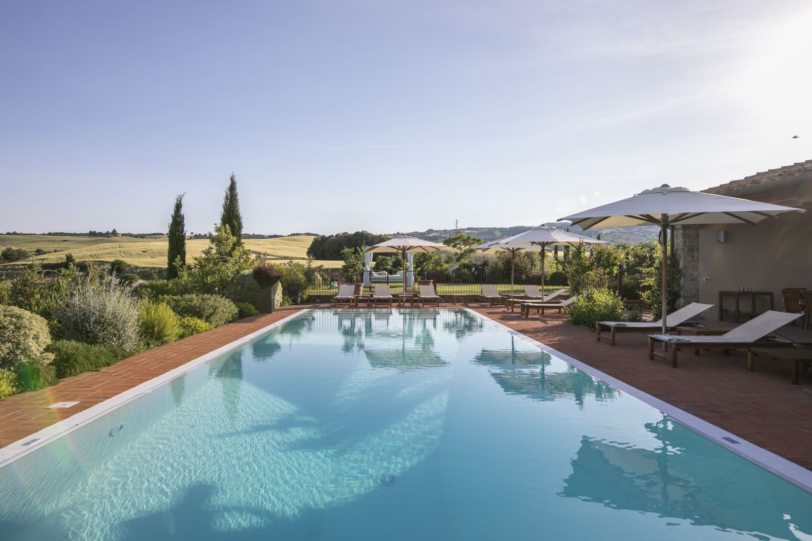 A lengthways view of the pool at Villa Papavero with hills and fields of Tuscany in the background