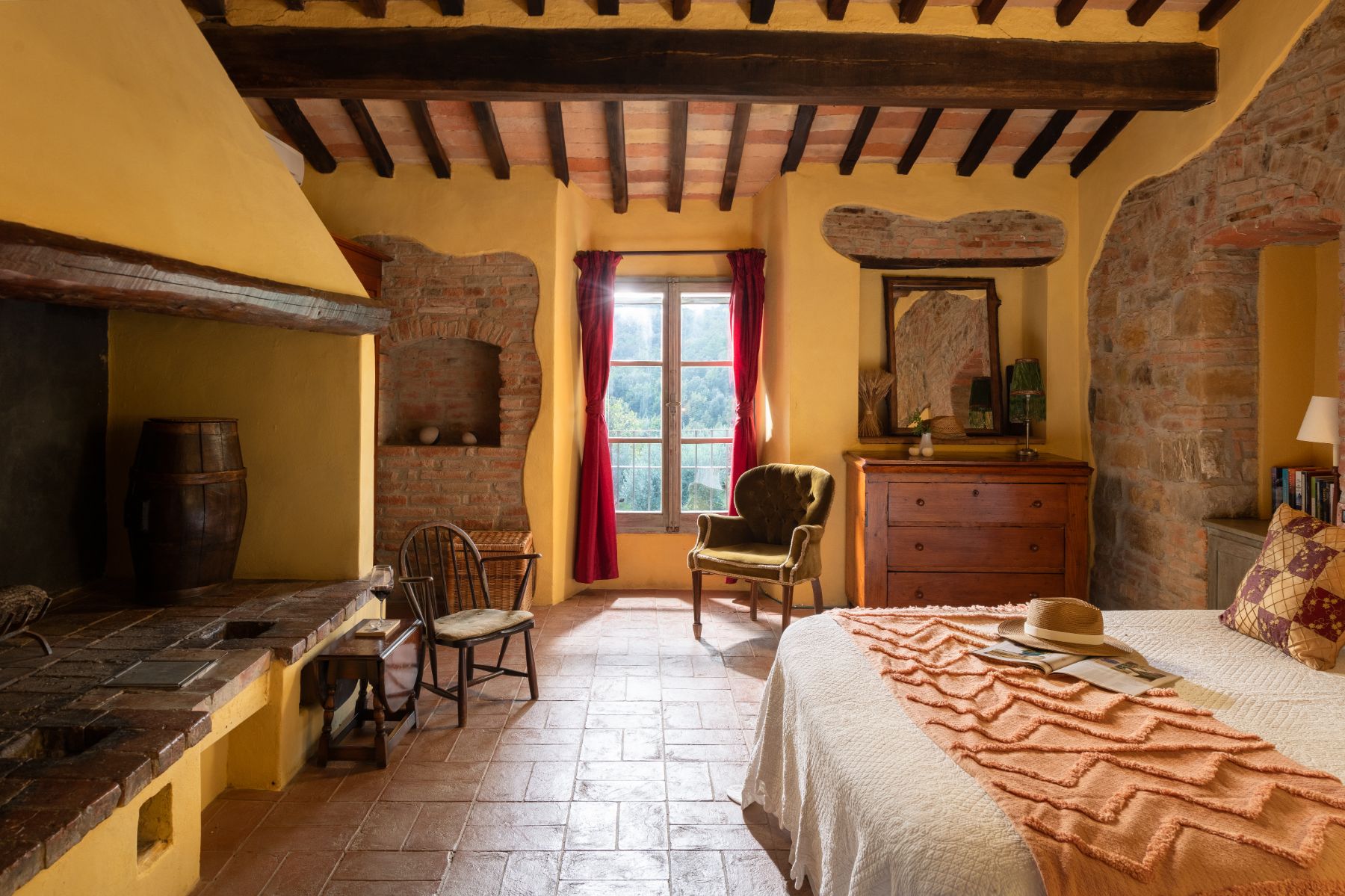 Bedroom with large double bed and armchair at Villa San Barberino in Tuscany