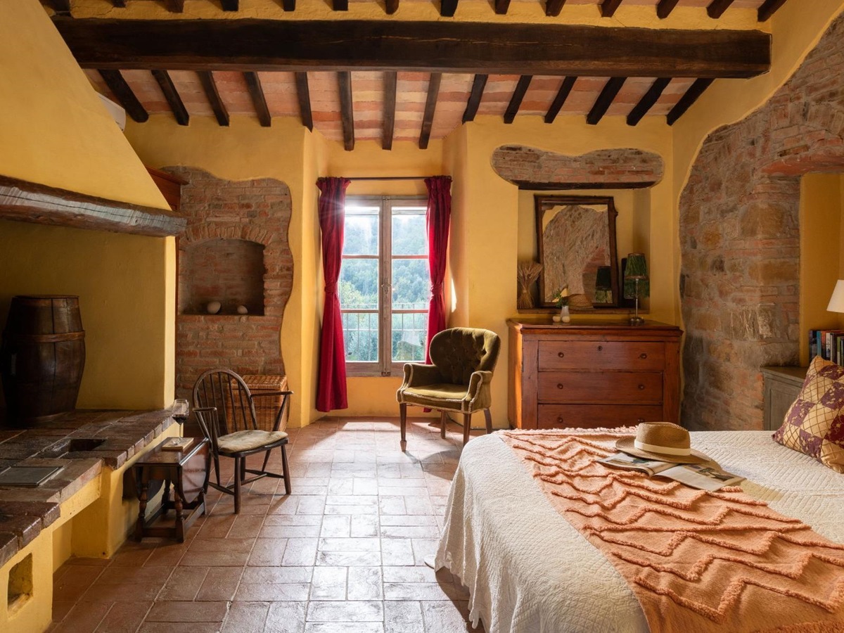 Bedroom with large double bed and armchair at Villa San Barberino in Tuscany