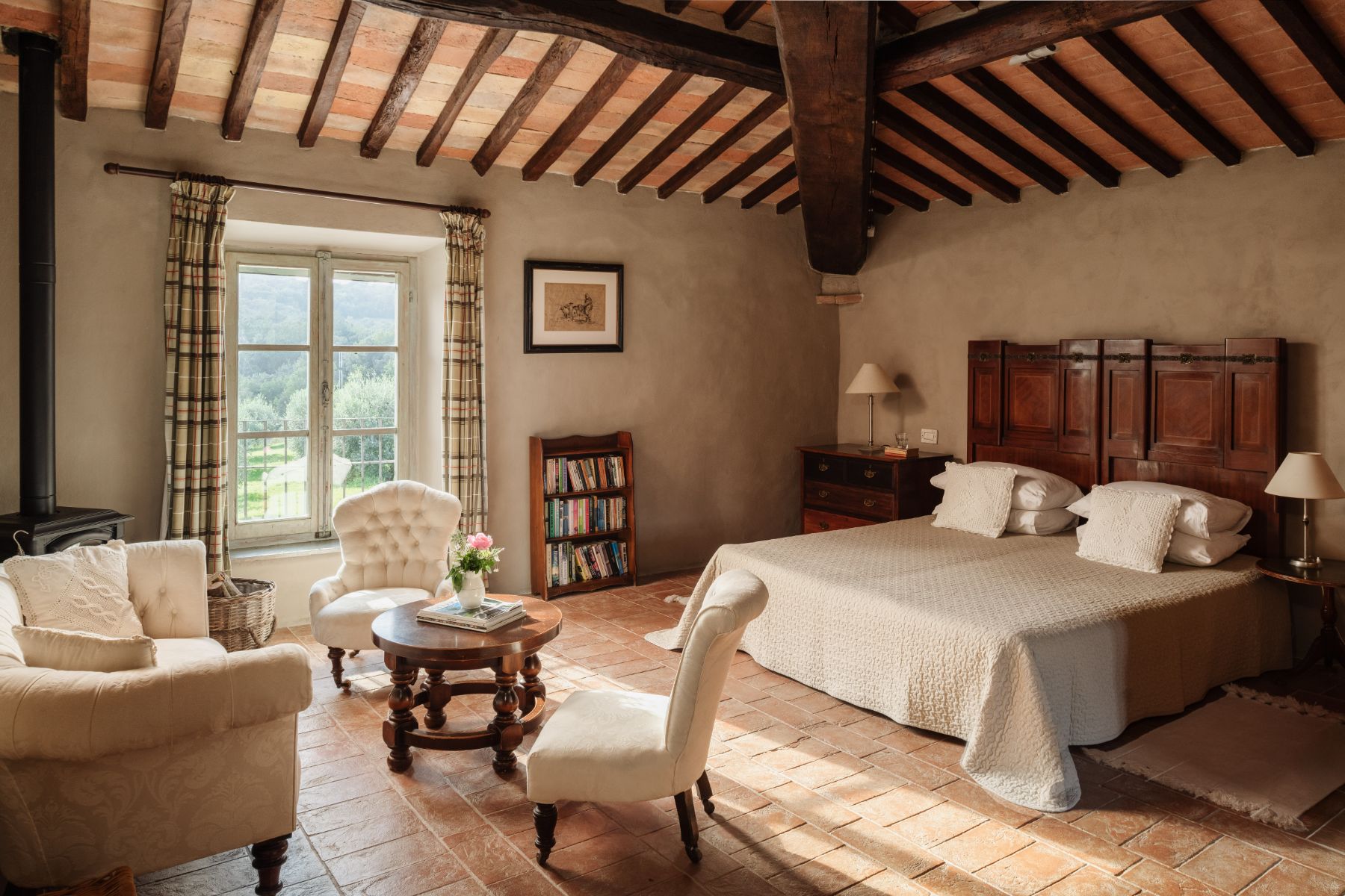 Bedroom with large double bed and three white armchairs at Villa San Barberino in Tuscany