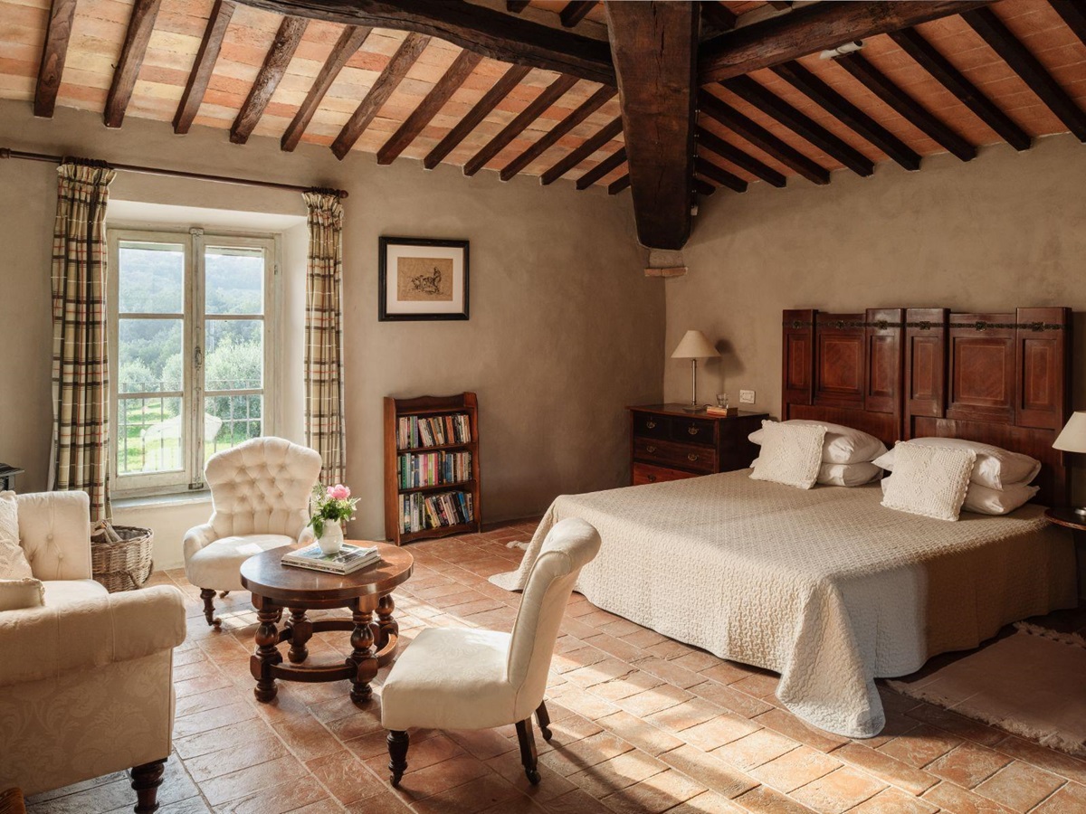 Bedroom with large double bed and three white armchairs at Villa San Barberino in Tuscany