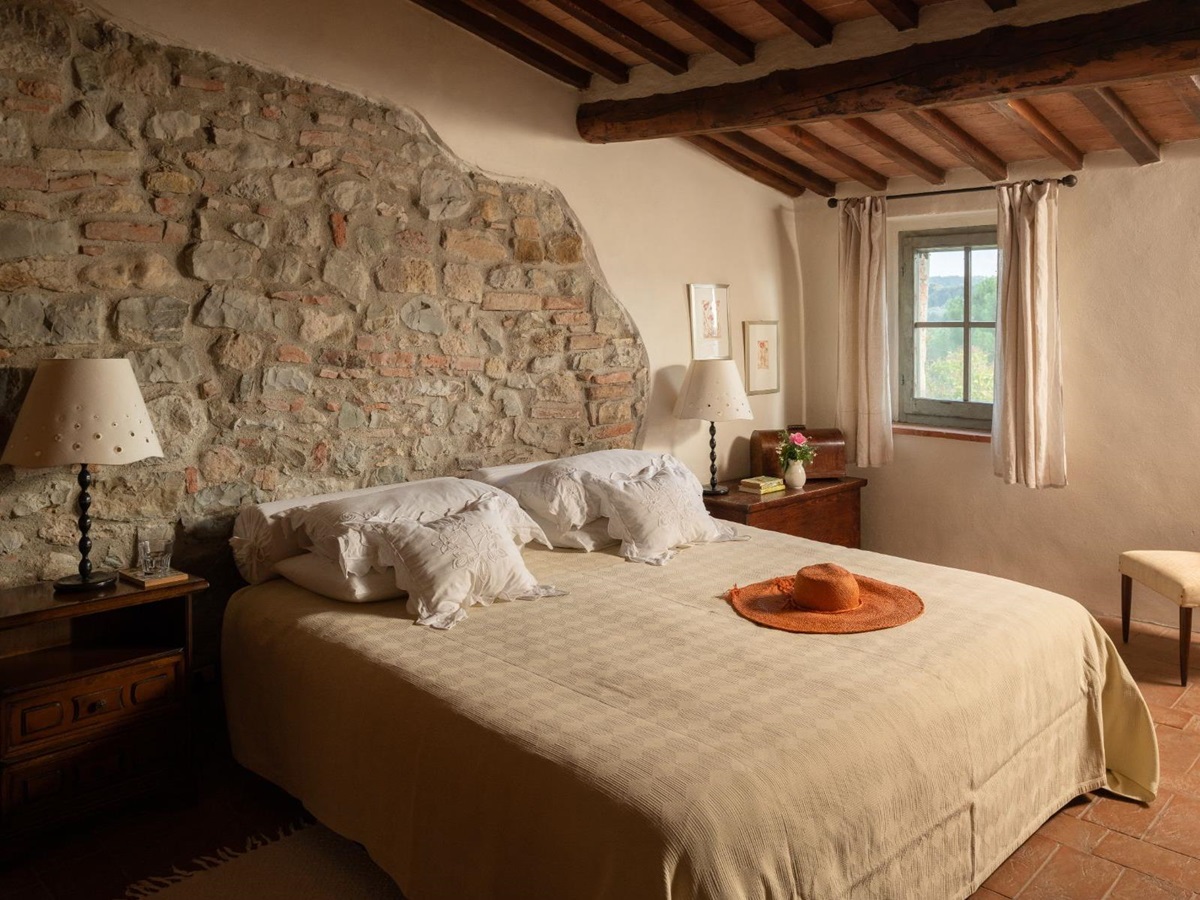 Bedroom with large double bed and traditional brick walls at Villa San Barberino in Tuscany