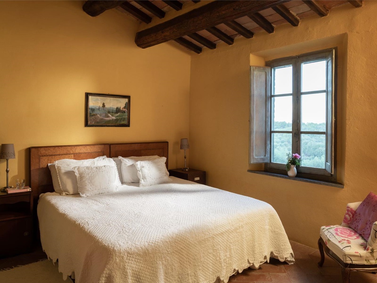 Bedroom with a large double bed and yellow wall paper at Villa San Barberino in Tuscany