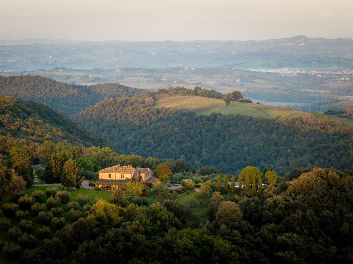 Drone view of Villa San Barberino surrounded by hills and trees in Tuscany