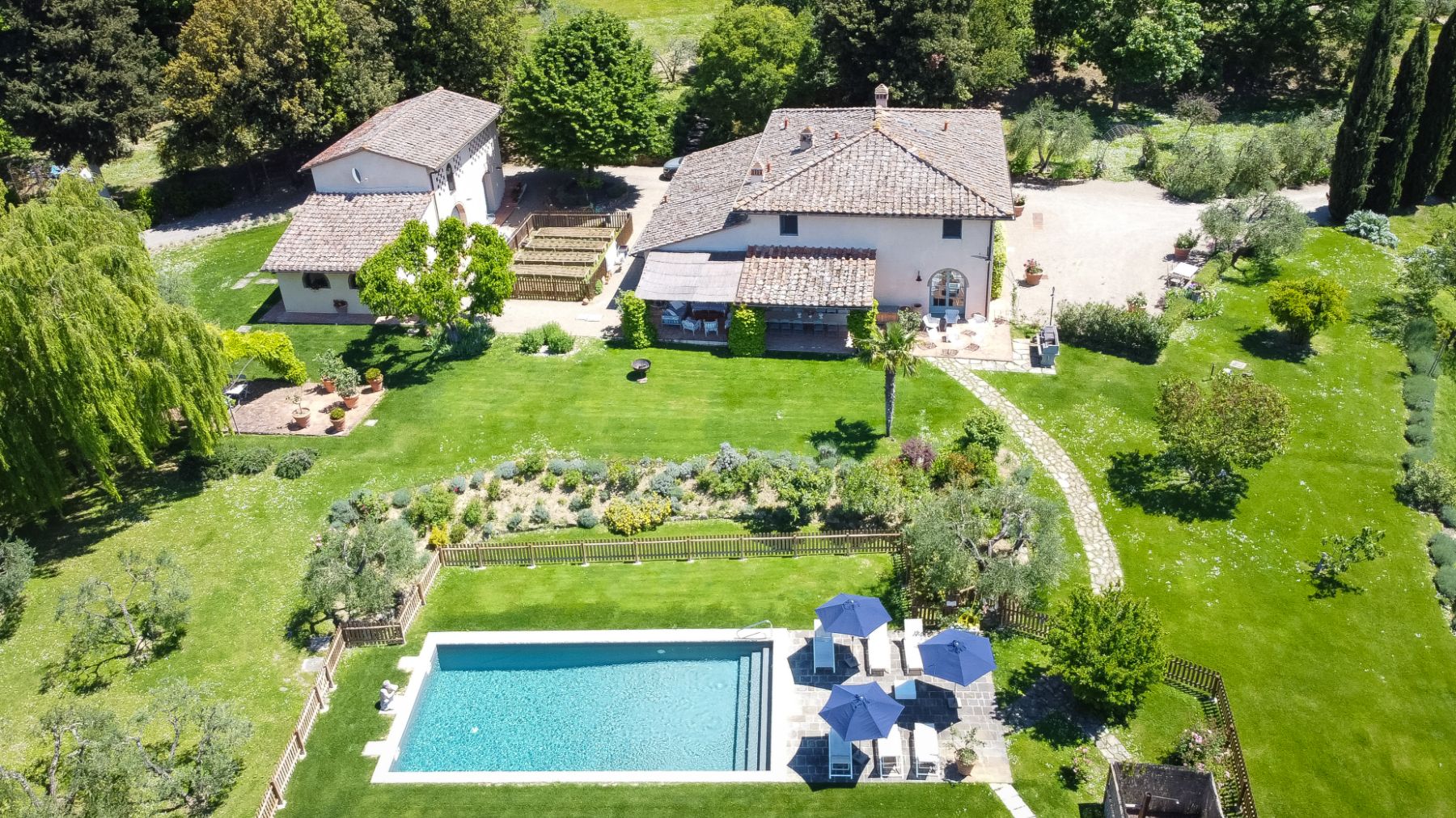 Drone view of Villa San Casciano and the outdoor pool surrounded by gardens in Tuscany