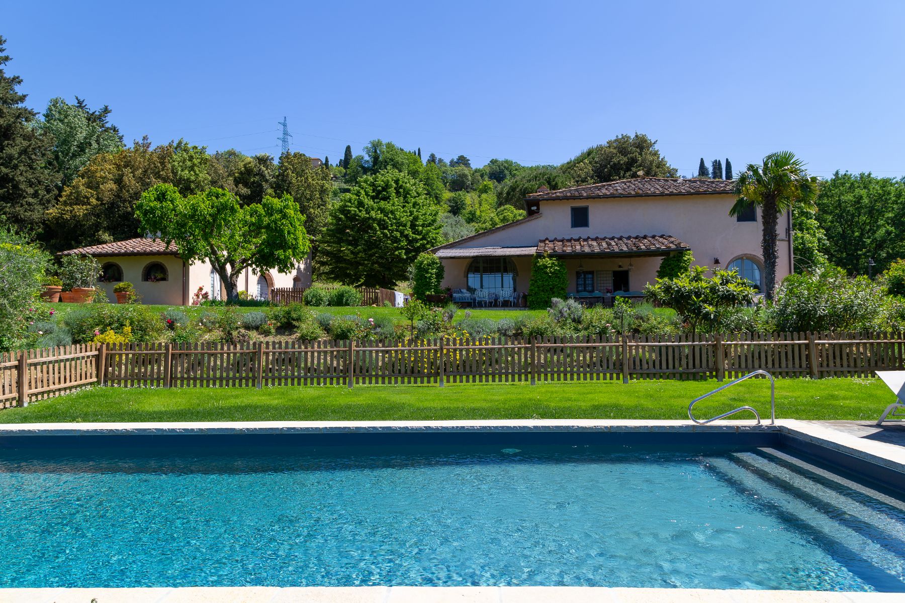 View from the outdoor pool at Villa San Casciano in Tuscany with view of the villa behind the fence