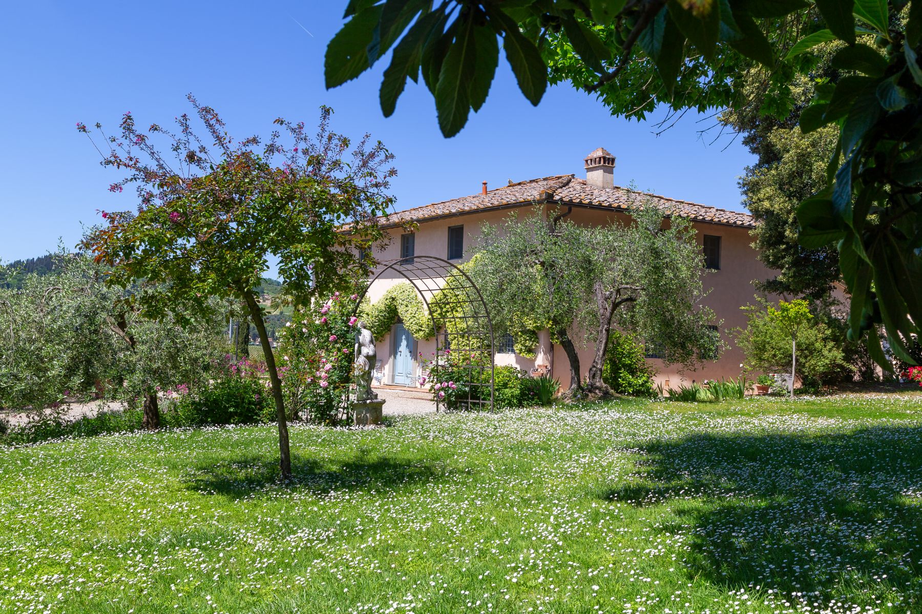 View of Villa San Casciano in Tuscany in front of the garden with trees and an archway