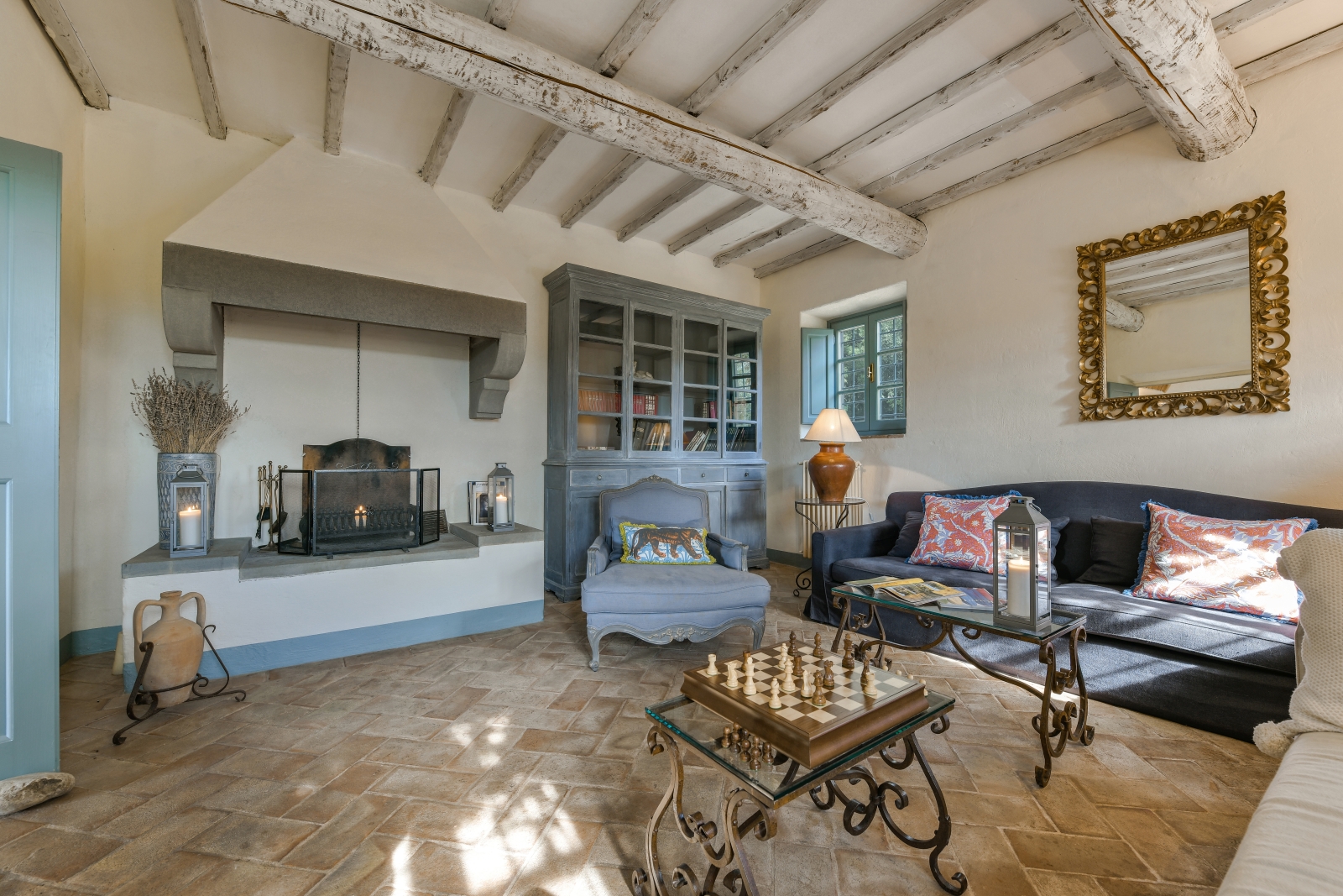 Living room with sofas, armchair, fireplace, coffee tables, chess board and cabinet at Villa San Casciano in Tuscany, Italy