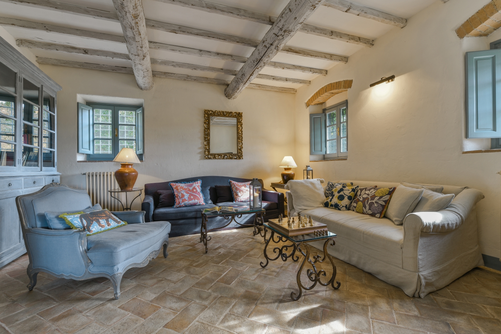 Living room with sofas, armchair, coffee tables, lamps, mirror, cabinet & chess board at Villa San Casciano in Tuscany, Italy