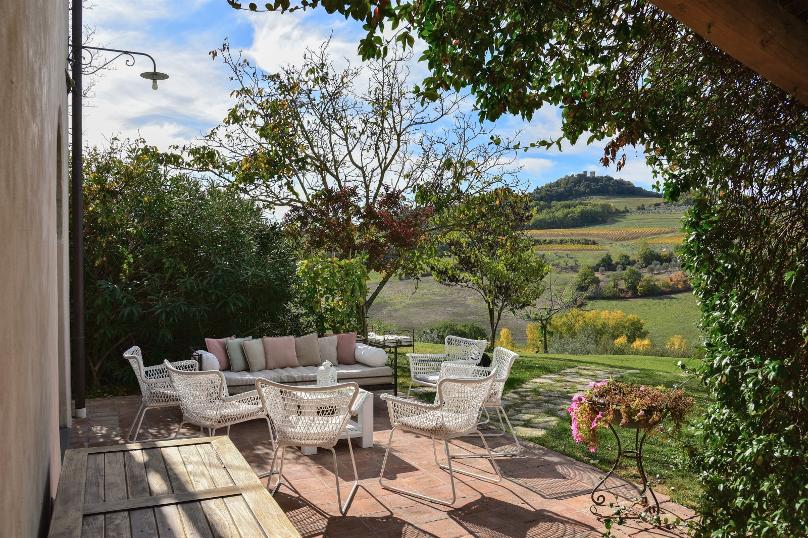 Outdoor seating area with chairs, sofa, table and view of garden and countryside at Villa San Casciano in Tuscany, Italy