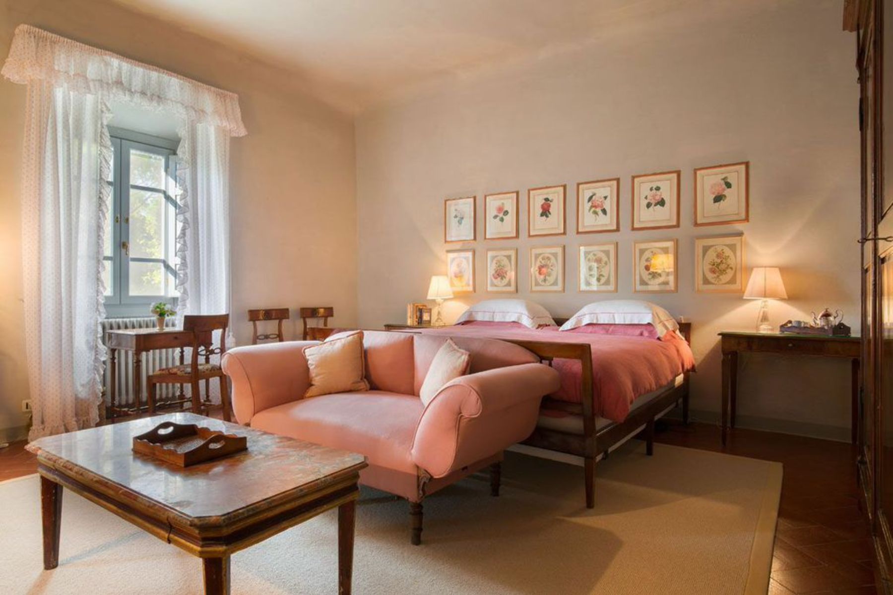Double bedroom featuring pictures on the wall and pink bedsheets at villa San Morello in Tuscany