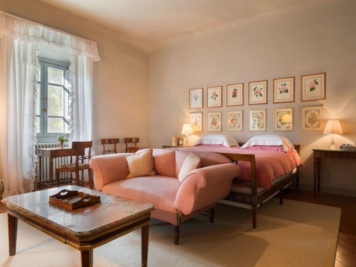 Double bedroom featuring pictures on the wall and pink bedsheets at villa San Morello in Tuscany