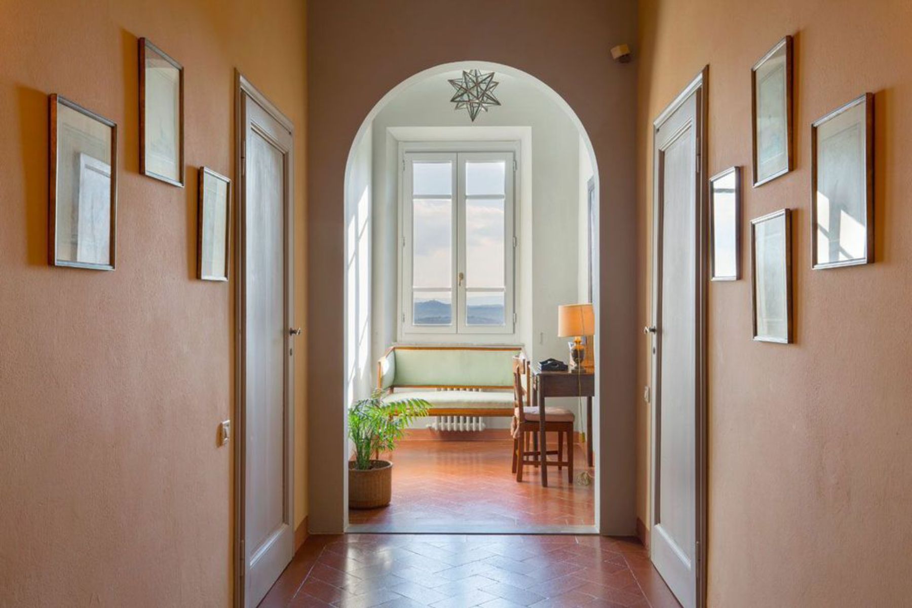 Hallway in Villa San Morello with an archway at the end and pictures on the walls