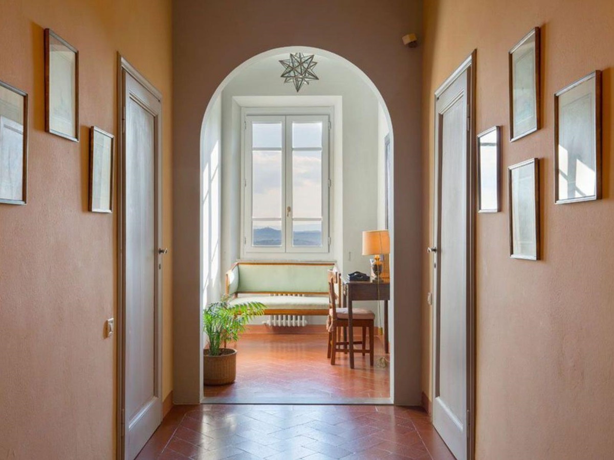 Hallway in Villa San Morello with an archway at the end and pictures on the walls