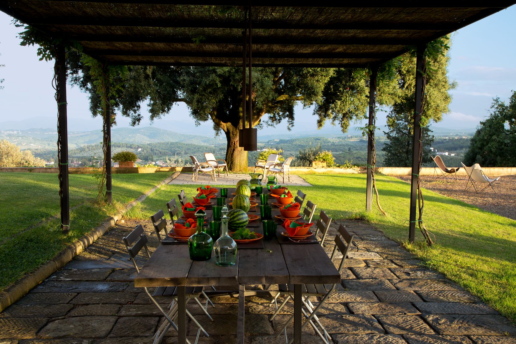 Outdoor dining area at Villa San Morello in Tuscany featuring a long table and views of hills in the background