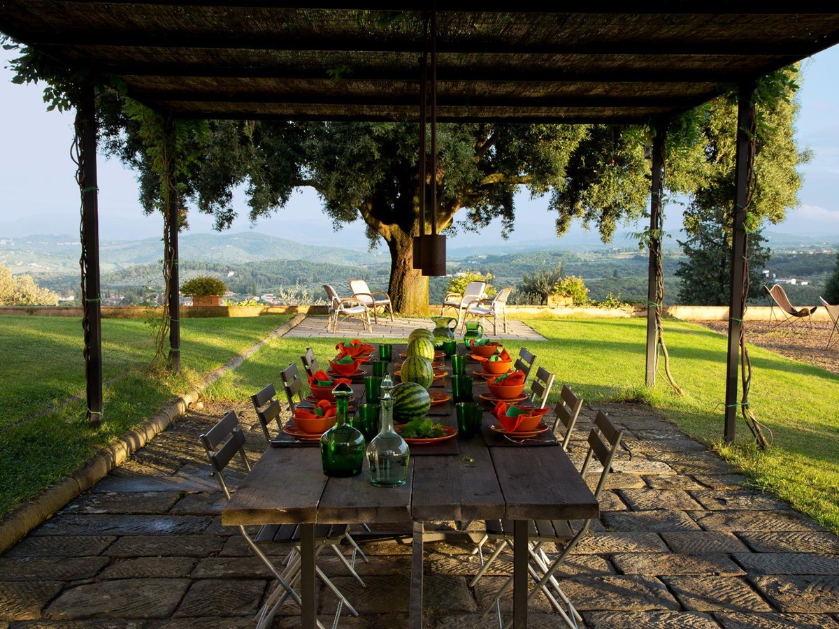 Outdoor dining area at Villa San Morello in Tuscany featuring a long table and views of hills in the background